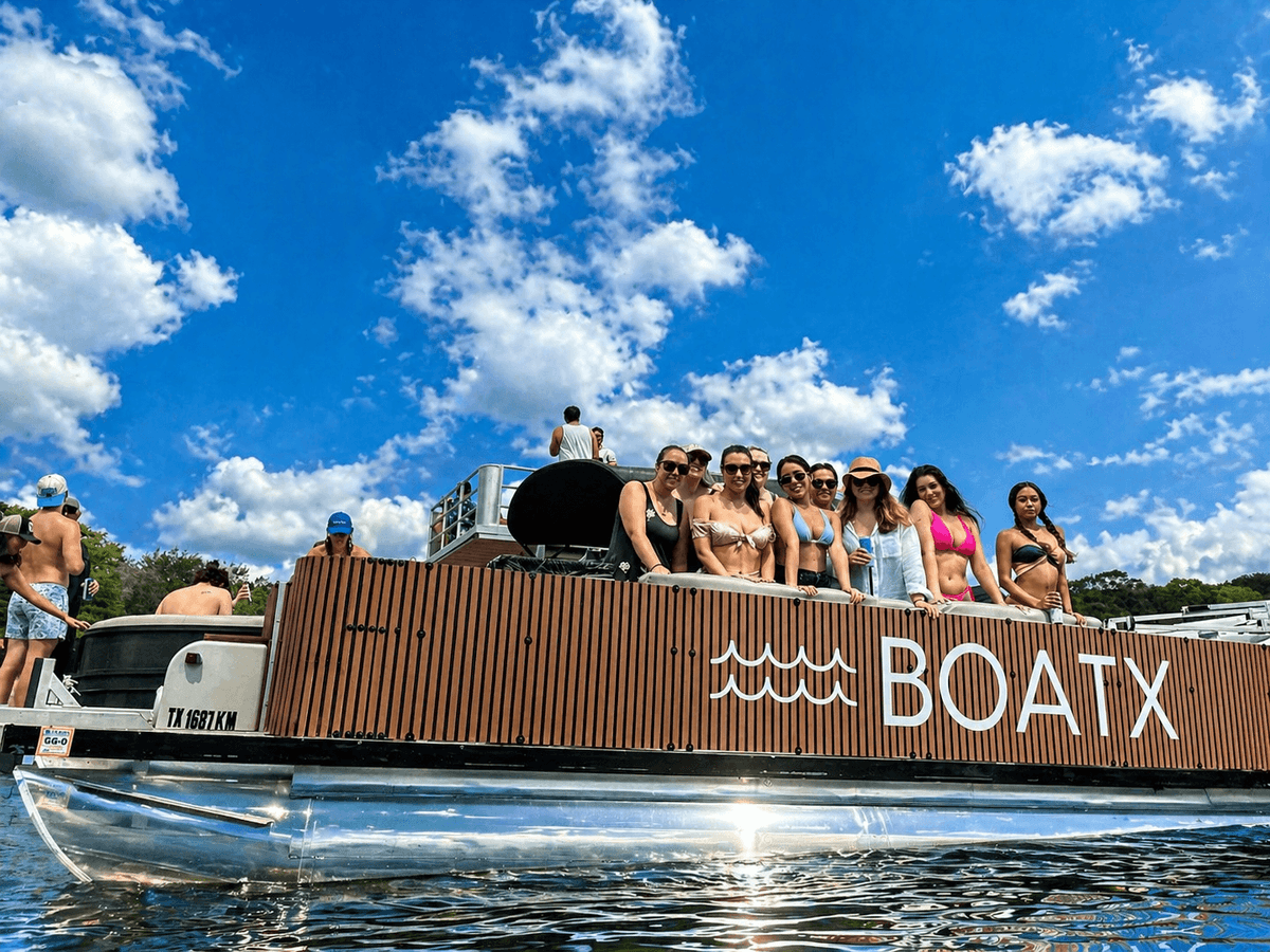 Group of friends posing on the upper deck of a BOATX double decker party boat on Lake Austin