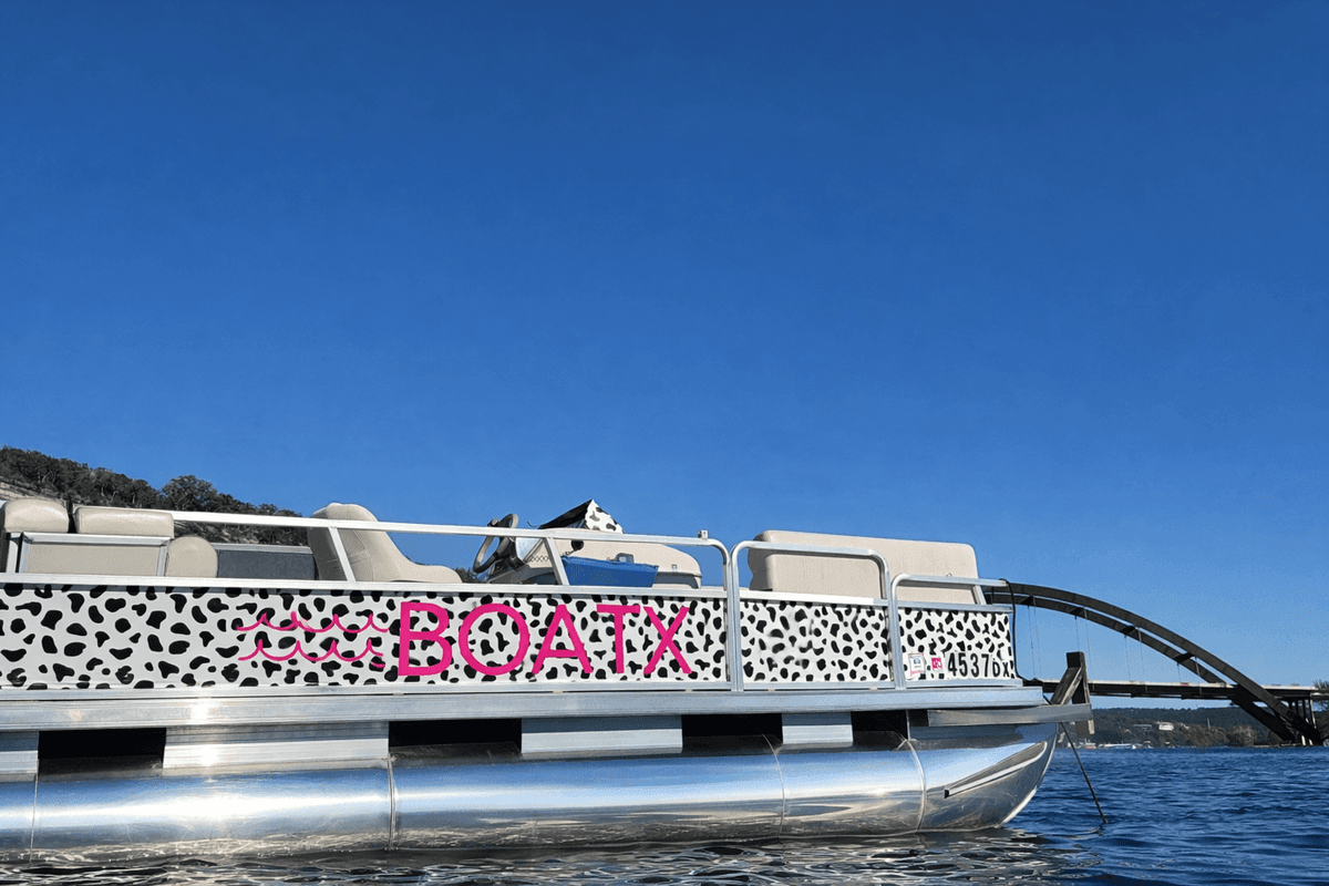 BOATX leopard-print wrapped pontoon boat near the 360 Pennybacker Bridge on Lake Austin