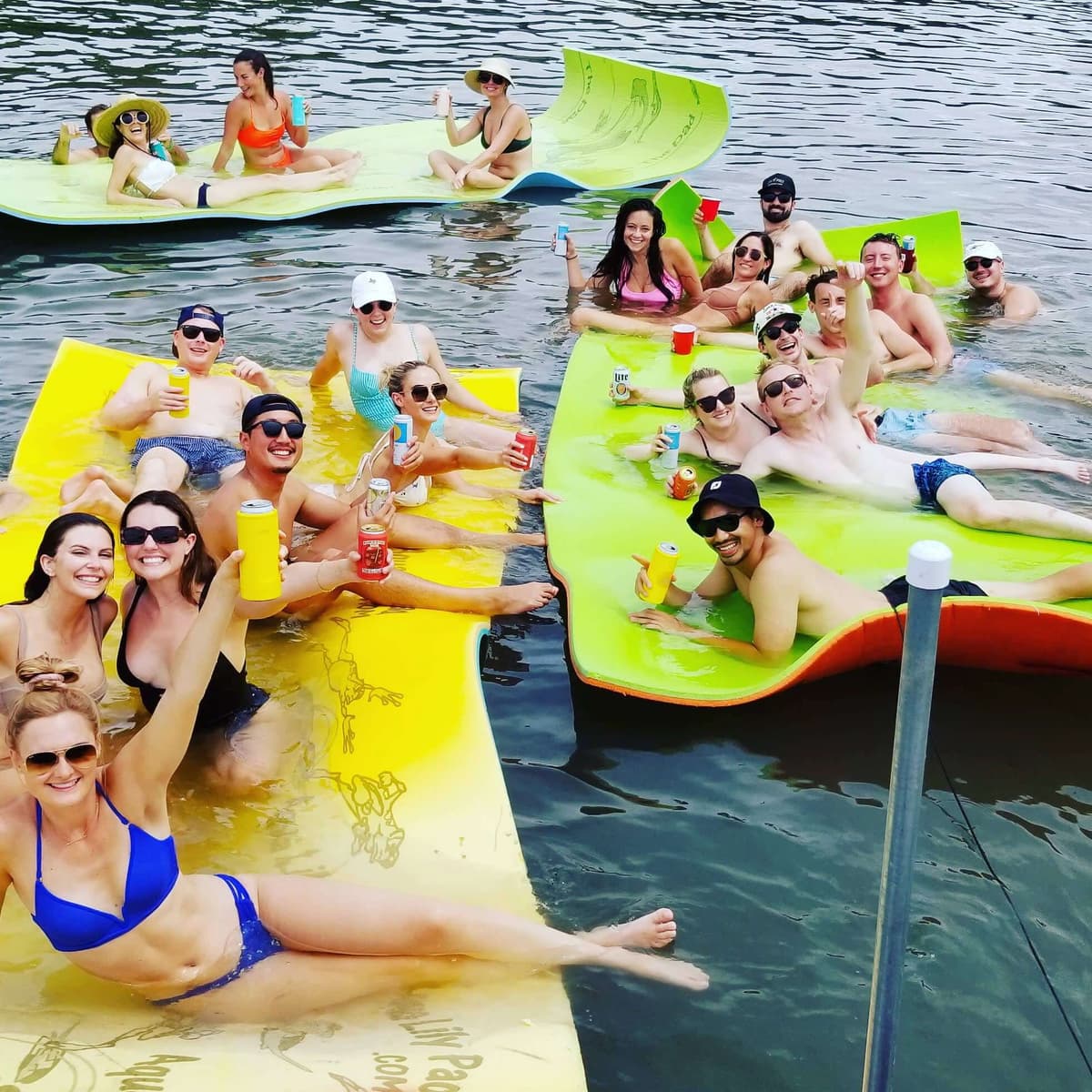 Group of friends floating on lily pads with drinks during Lake Austin boat rental party