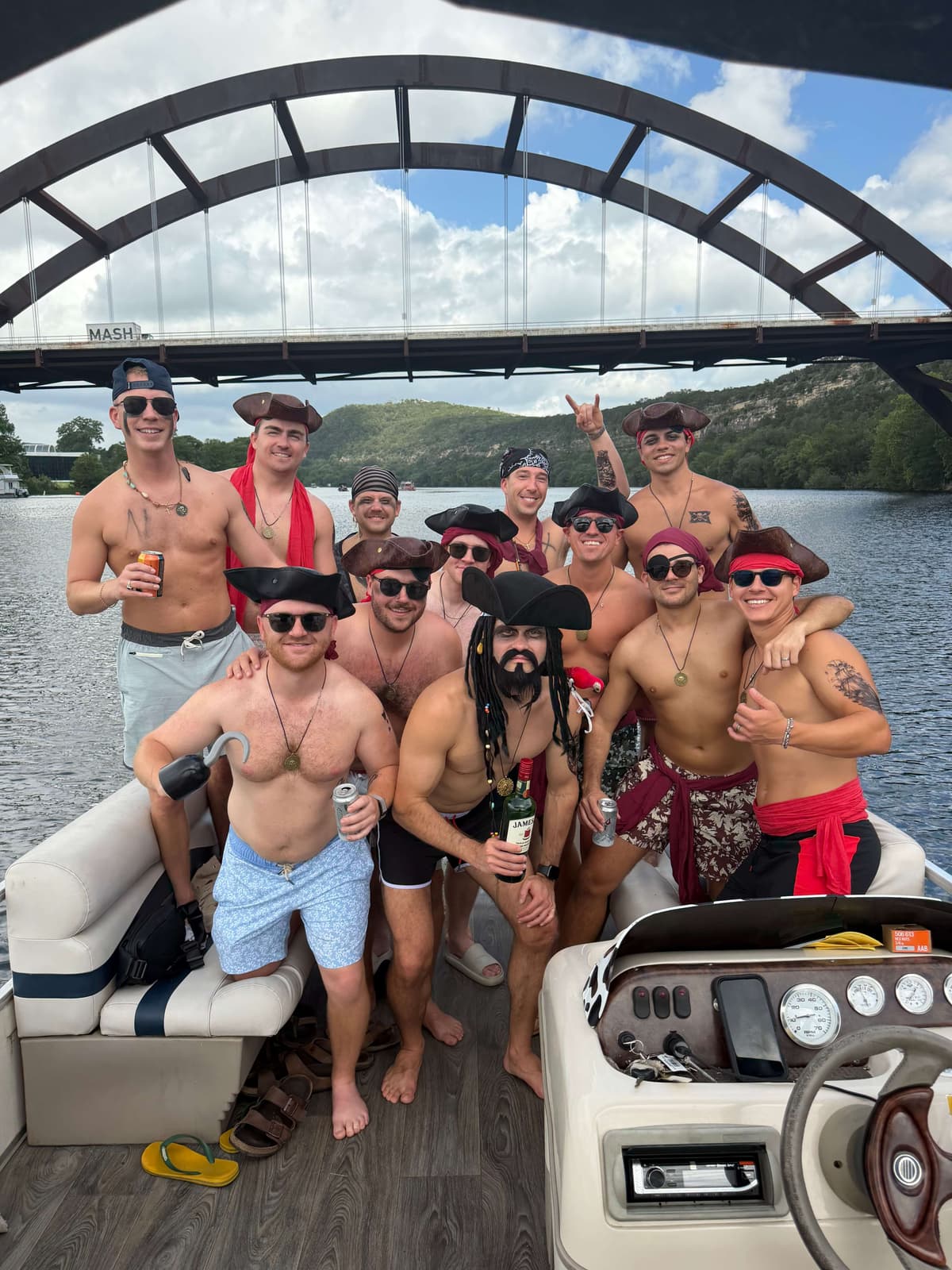 Bachelor party group in pirate costumes celebrating on a BOATX pontoon under the 360 Pennybacker Bridge Lake Austin
